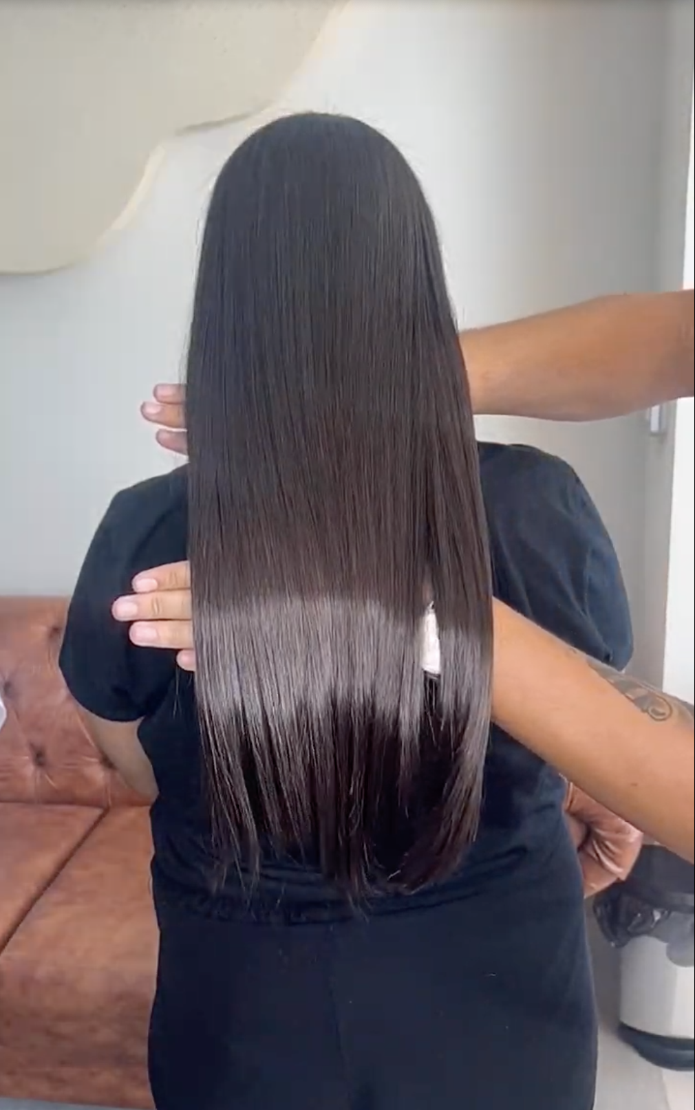 Cabelo liso preto longo sendo finalizado pelo cabeleireiro — costas