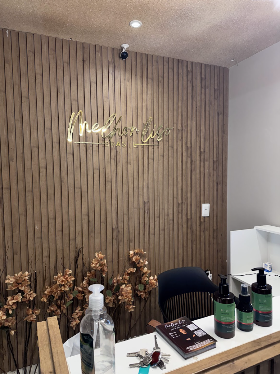 Recepção com logo dourado na parede de madeira ripada
